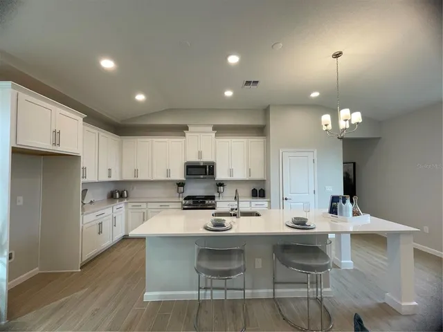 a kitchen with a dining table chairs stainless steel appliances and cabinets