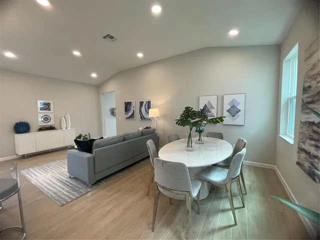 a living room with furniture and a dining table with wooden floor