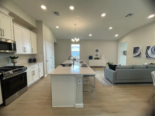 a large white kitchen with kitchen island a sink a stove and a refrigerator