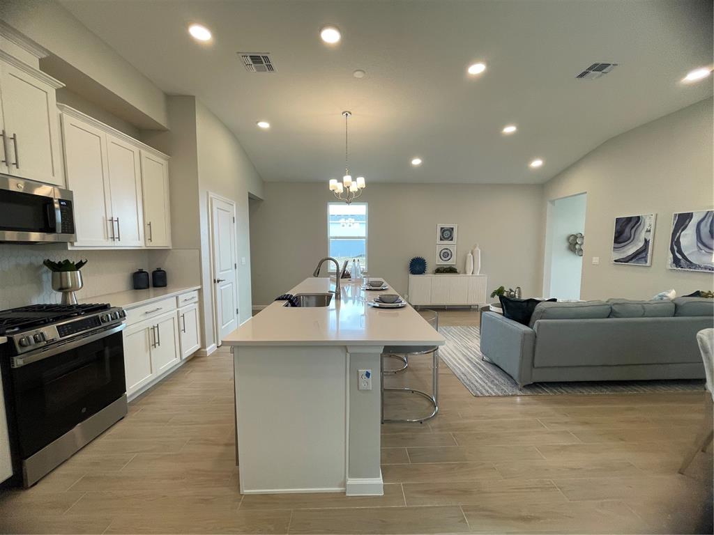 5288 Ctr Lk Rnch Boulevard St. Cloud, FL 34771 - Photo 22 of 31 a large white kitchen with kitchen island a sink a stove and a refrigerator