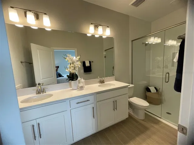 a bathroom with a double vanity sink toilet mirror and shower