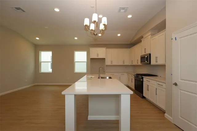 a kitchen with kitchen island granite countertop a sink cabinets and wooden floor