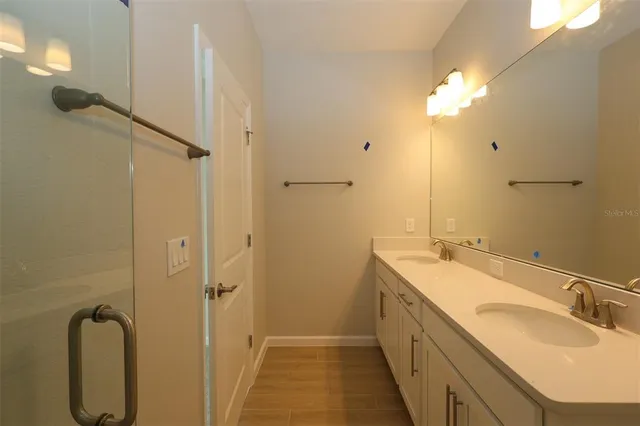 a bathroom with a double vanity sink a mirror and a shower