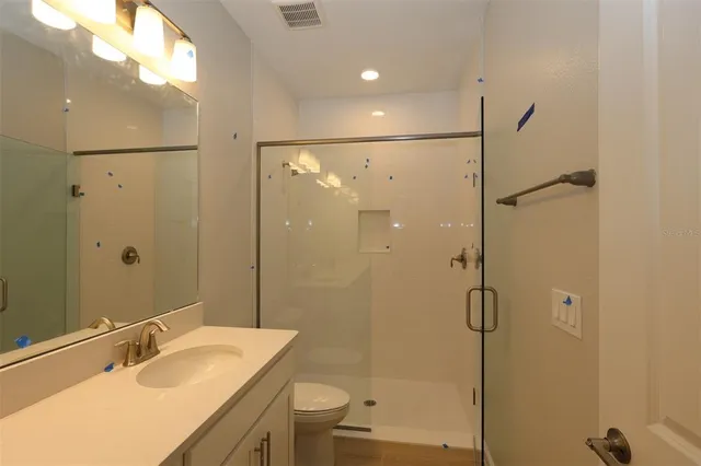 a bathroom with a shower sink vanity mirror and toilet