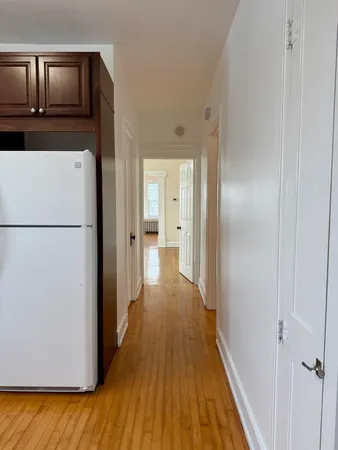 a view of a hallway with wooden floor and cabinets