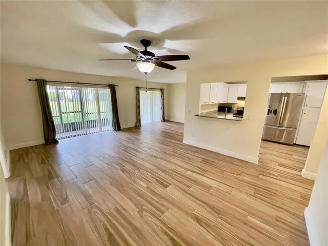 an empty room with wooden floor fan and windows