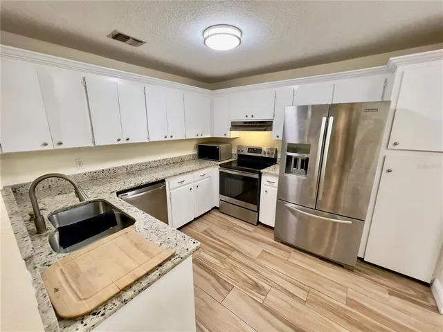 a kitchen with a refrigerator sink and cabinets