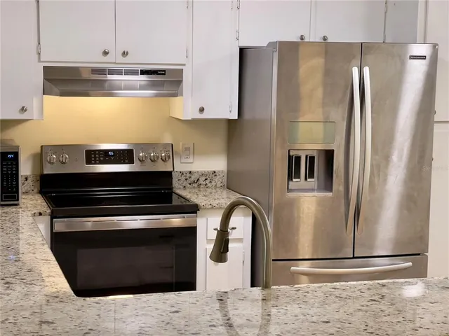 a kitchen with stainless steel appliances granite countertop a refrigerator and a stove top oven