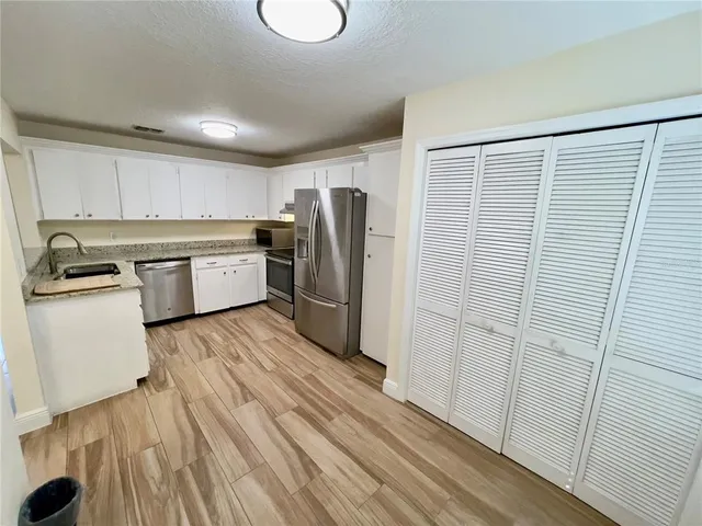 a kitchen with a refrigerator a sink and dishwasher with wooden floor