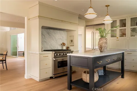 a stove top oven sitting inside of a kitchen with stainless steel appliances wooden floor