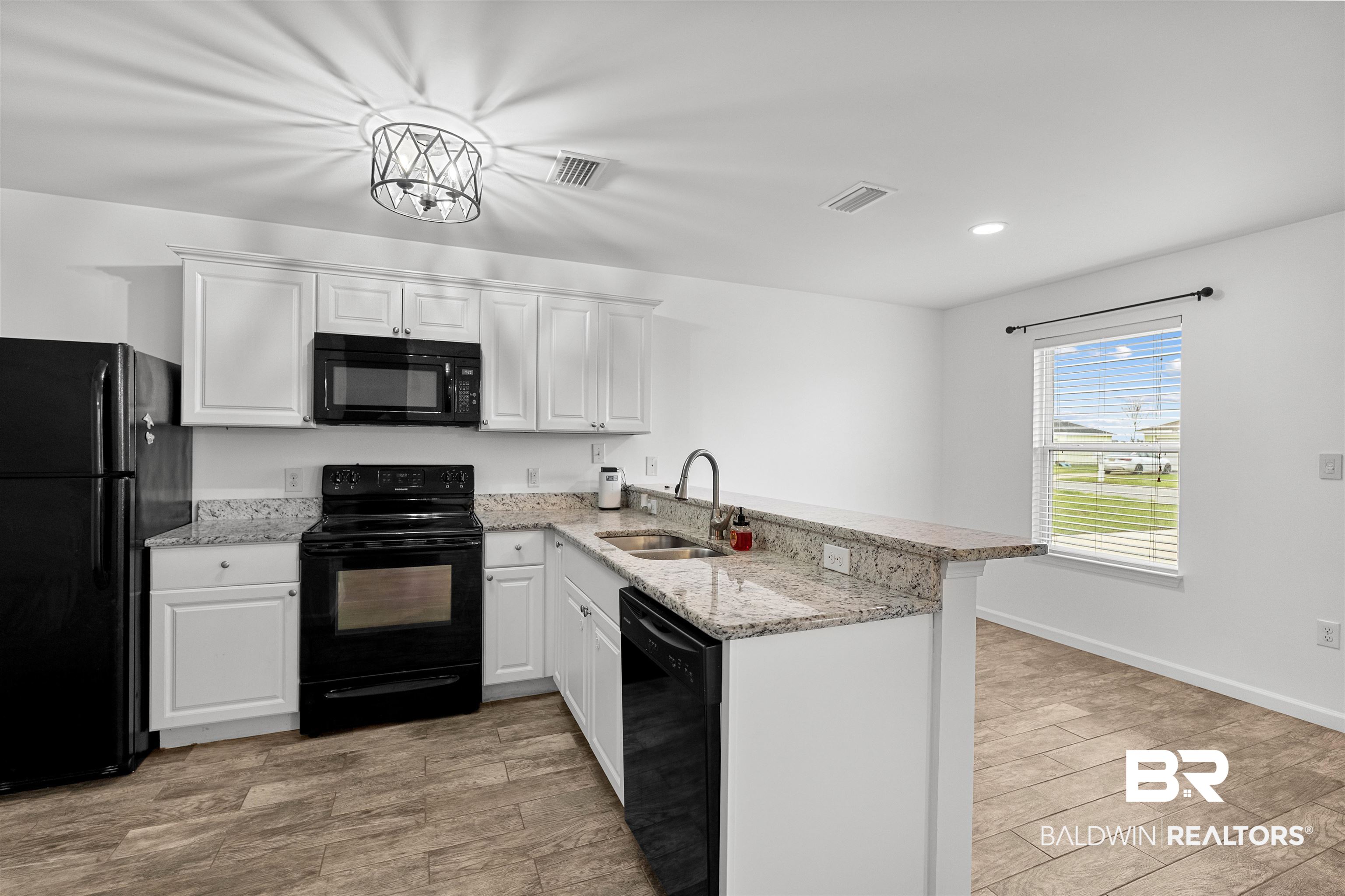 15131 Marem Drive Foley, AL 36535 - Photo 5 of 13 Kitchen featuring black appliances, a peninsula, white cabinets, wood finish floors, and recessed lighting