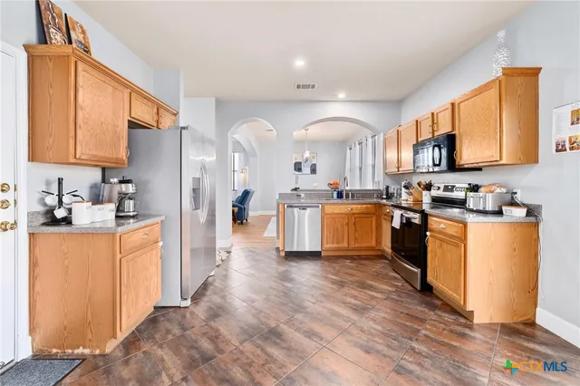 a kitchen with stainless steel appliances granite countertop a stove a sink dishwasher and a refrigerator