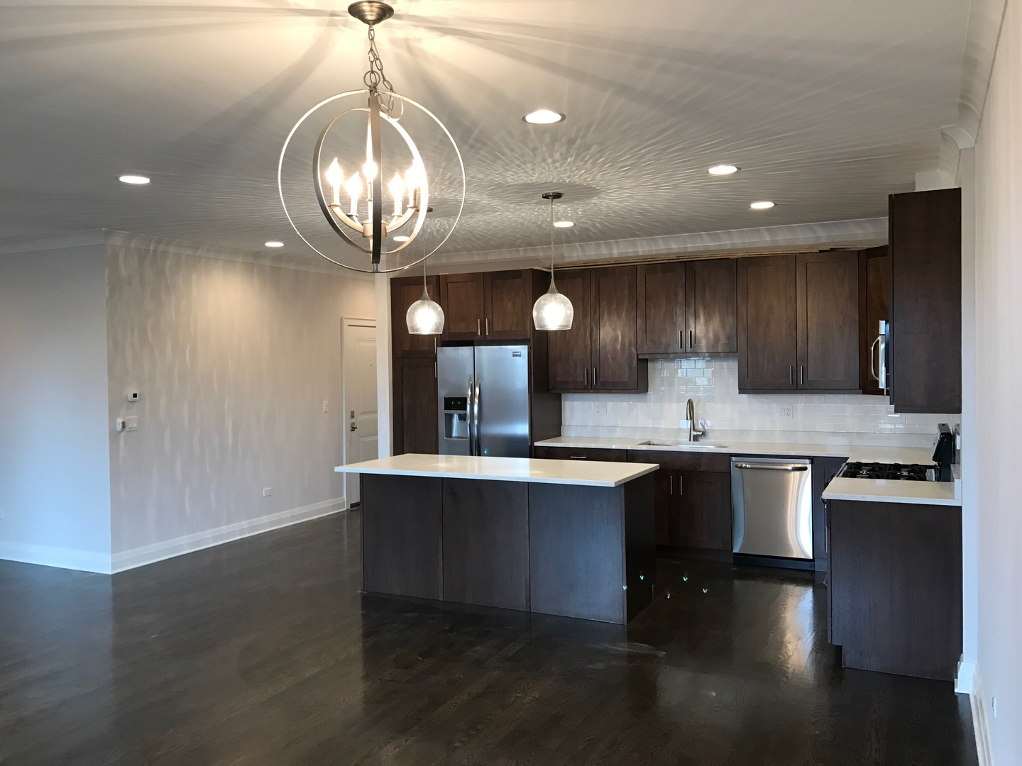 1843 West Irving Park Road, Unit 3 Chicago, IL 60613 - Photo 17 of 34 a kitchen with stainless steel appliances granite countertop a sink stove a refrigerator and a dining table with wooden floor
