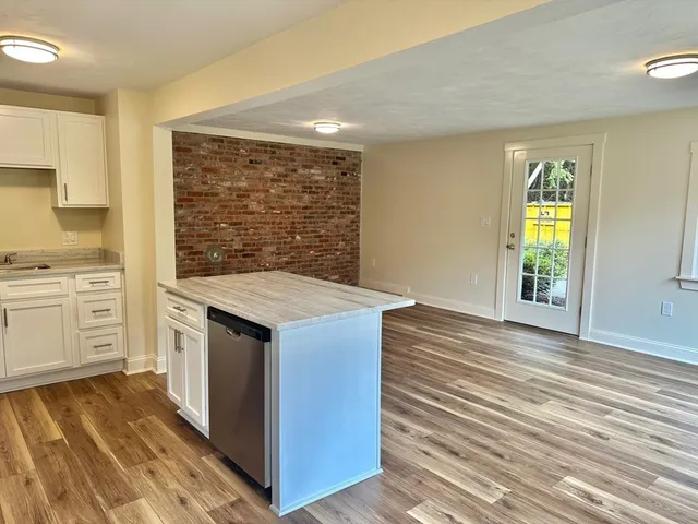 a kitchen with white cabinets and wooden floor