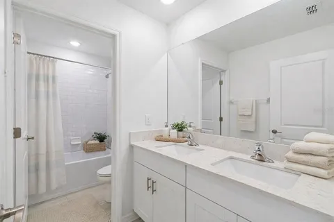 a bathroom with a double vanity sink toilet mirror and shower
