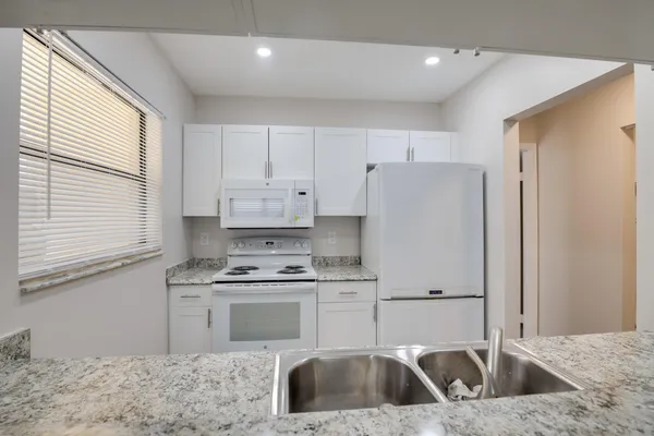 a kitchen with white cabinets and white appliances