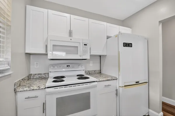 a kitchen with granite countertop white cabinets and a sink