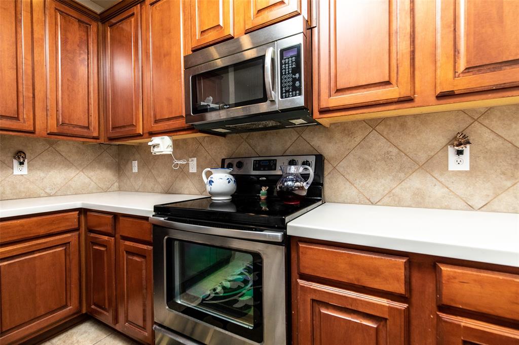 3118 Bedford Road Bedford, TX 76021 - Photo 12 of 29 Kitchen featuring wood cabinetry, light-toned countertops, a stainless steel electric range, and an over-the-range microwave