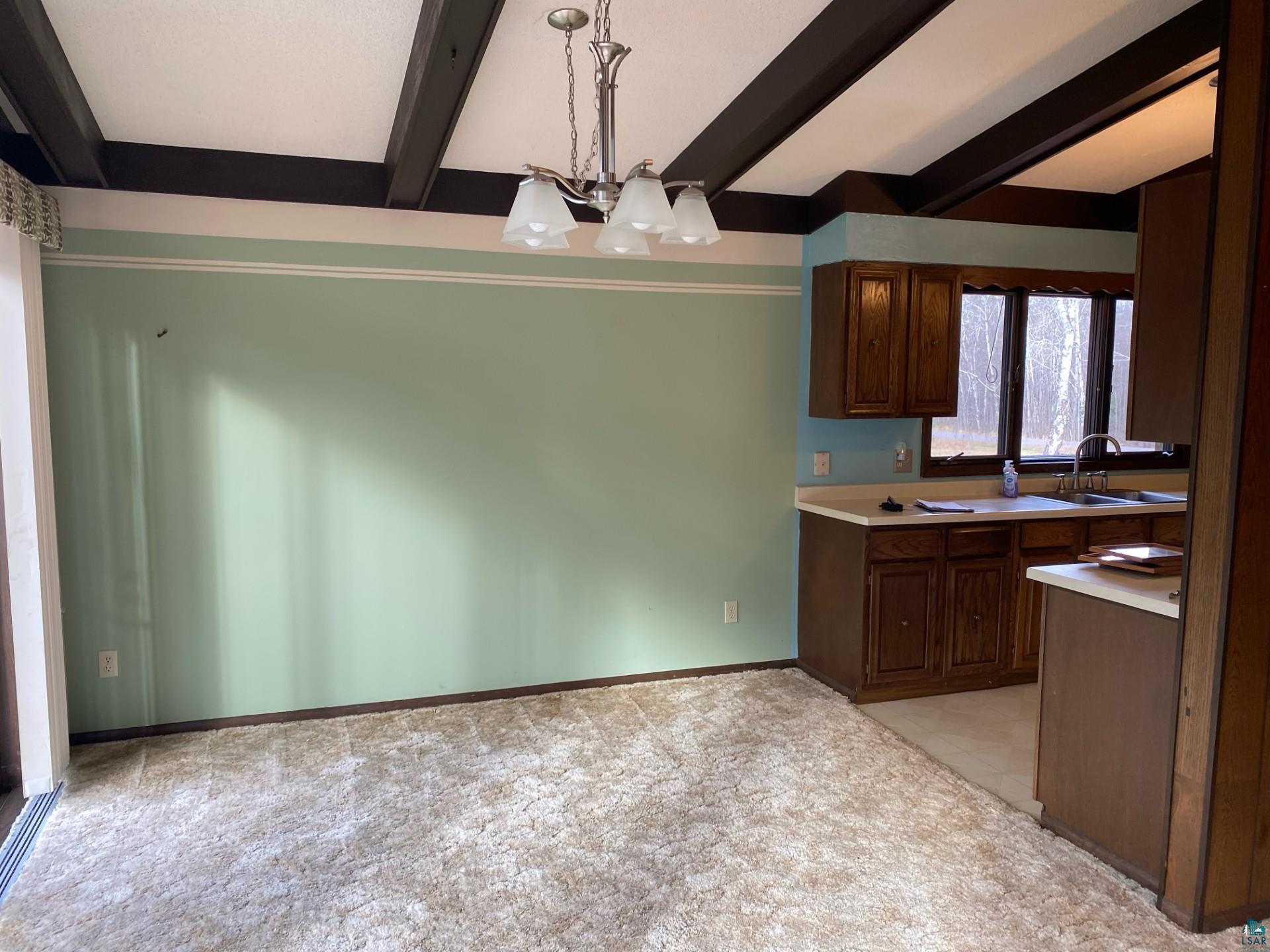 11316 East Timber Ridge Drive Lake Nebagamon, WI 54849 - Photo 12 of 27 Kitchen with a chandelier, light carpet, sink, beam ceiling, and decorative light fixtures