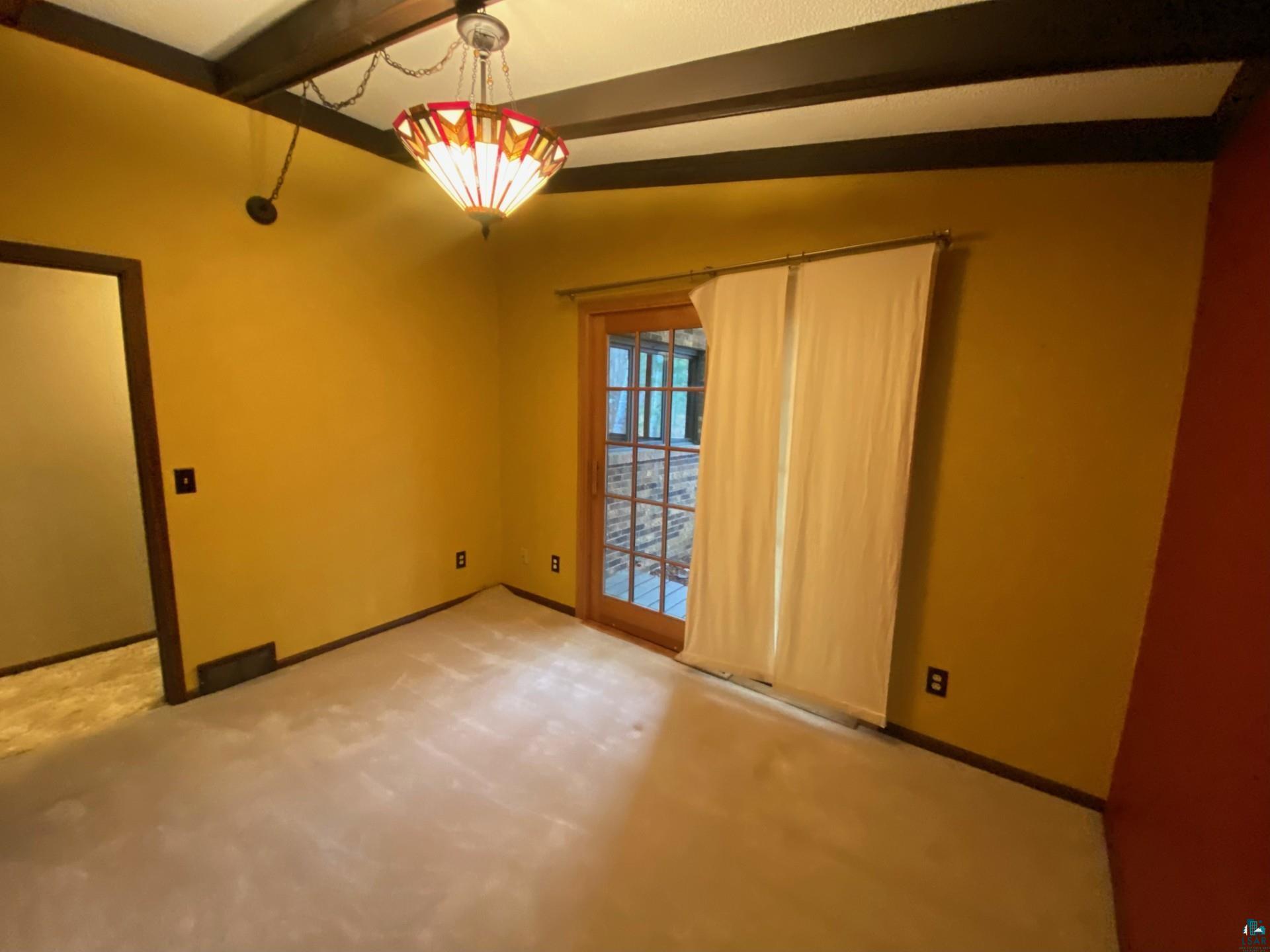 11316 East Timber Ridge Drive Lake Nebagamon, WI 54849 - Photo 15 of 27 Unfurnished room with light carpet and vaulted ceiling with beams