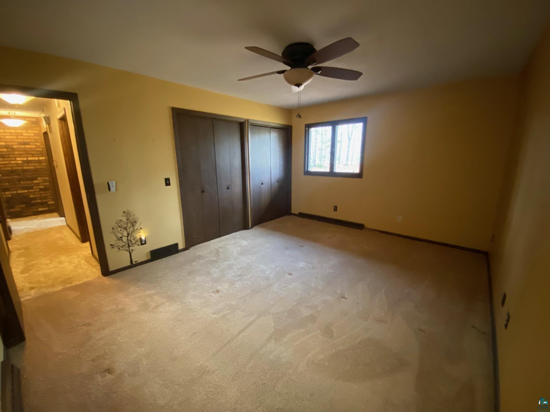 11316 East Timber Ridge Drive Lake Nebagamon, WI 54849 - Photo 21 of 27 Unfurnished bedroom featuring multiple closets, light colored carpet, and ceiling fan
