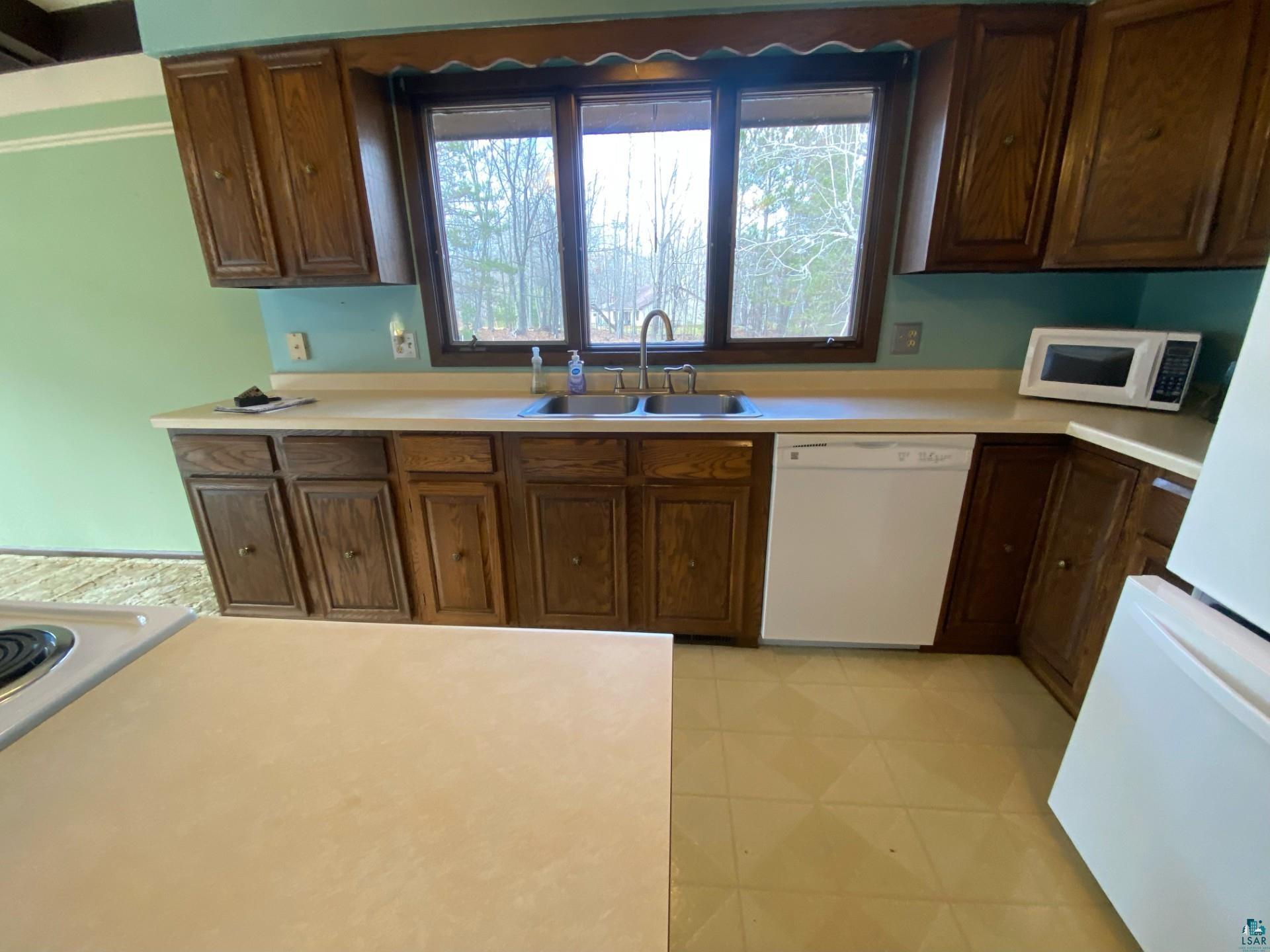11316 East Timber Ridge Drive Lake Nebagamon, WI 54849 - Photo 10 of 27 Kitchen with white appliances, sink, and light tile patterned flooring