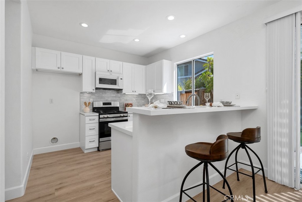 56 Acorn Ridge Rancho Santa Margarita, CA 92688 - Photo 19 of 57 Kitchen / Breakfast Bar: A raised breakfast bar adds casual seating, while white cabinetry, stainless-steel appliances, and an open layout connect the kitchen to the dining area.