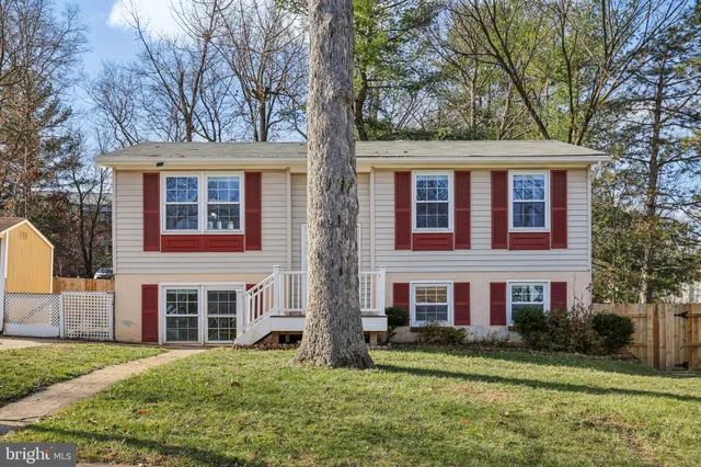 a view of a yard in front of a brick house with large windows