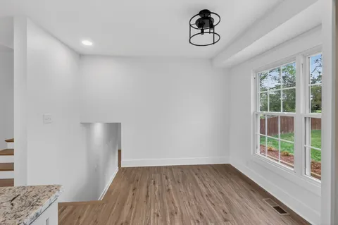 a view of an empty room with wooden floor fireplace and a window