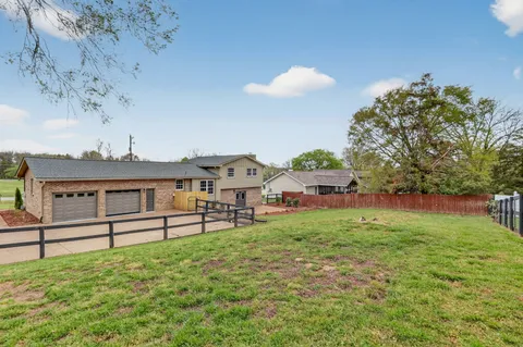 a view of house with outdoor space and tree in front of it