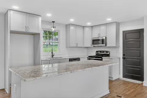 a kitchen with stainless steel appliances granite countertop a sink stove and refrigerator