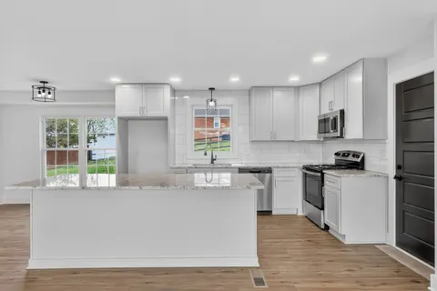 a kitchen with stainless steel appliances granite countertop a sink a stove and a wooden floors