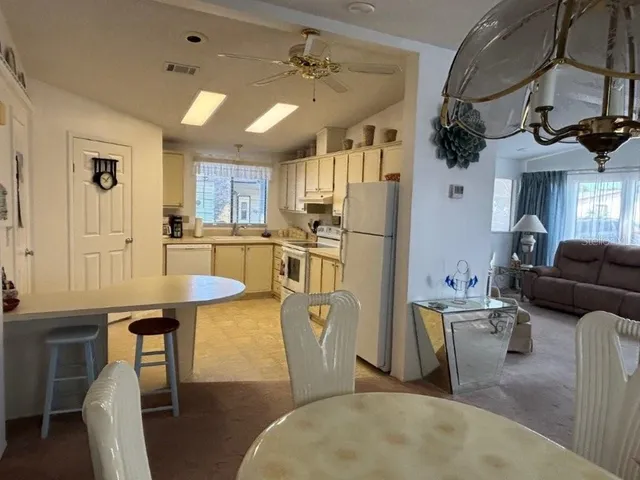 a kitchen with stainless steel appliances granite countertop a stove a refrigerator a kitchen island a table and chairs