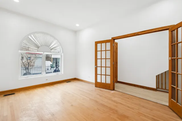 a view of an empty room with a window and wooden floor