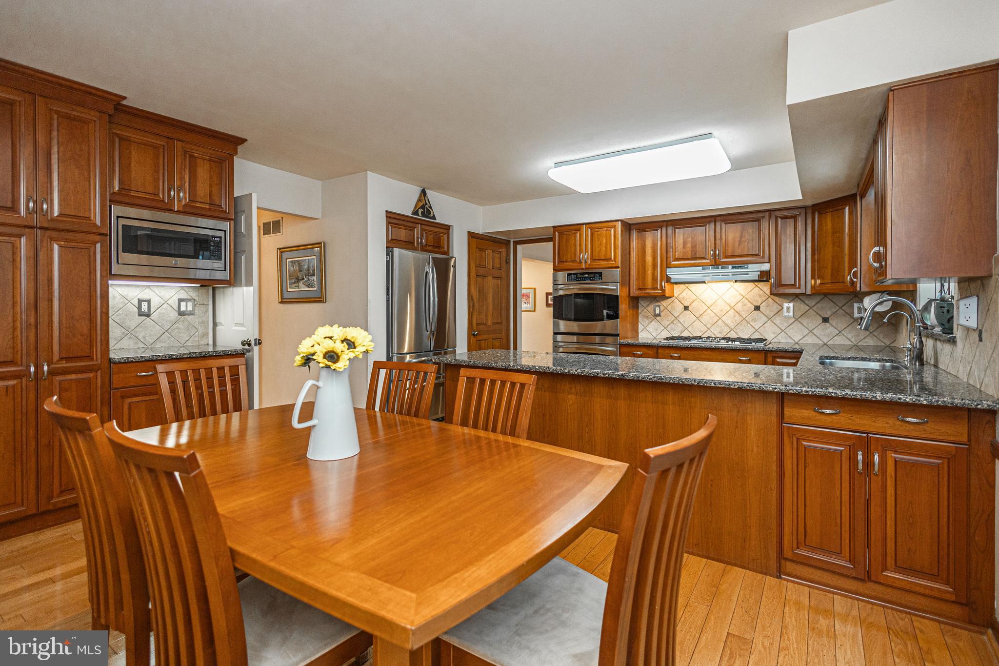 649 Teich Drive Yardley, PA 19067 - Photo 15 of 63 a kitchen with stainless steel appliances granite countertop a stove a sink a dining table and chairs