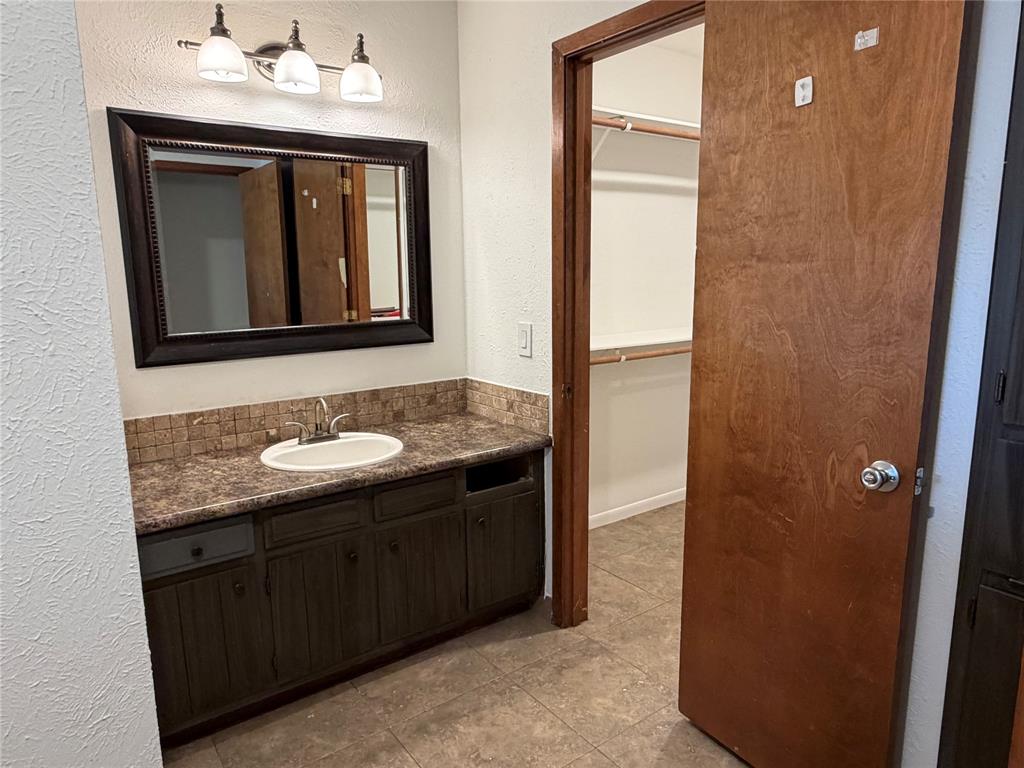 314 West 5th Street Springtown, TX 76082 - Photo 16 of 21 a bathroom with a granite countertop sink and a mirror