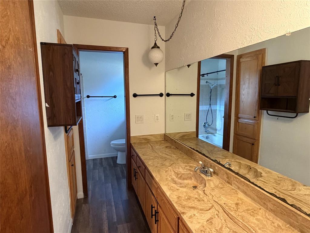 314 West 5th Street Springtown, TX 76082 - Photo 18 of 21 a spacious bathroom with a granite countertop sink a toilet a mirror and shower