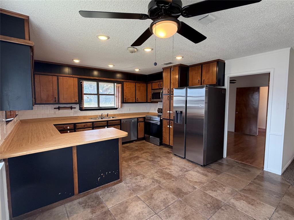 314 West 5th Street Springtown, TX 76082 - Photo 9 of 21 a kitchen with stainless steel appliances granite countertop a sink a refrigerator and a stove top oven