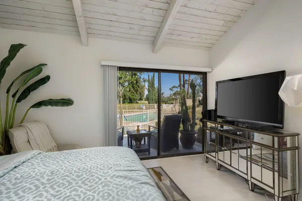 a bedroom with a bed and a flat tv screen next to a window