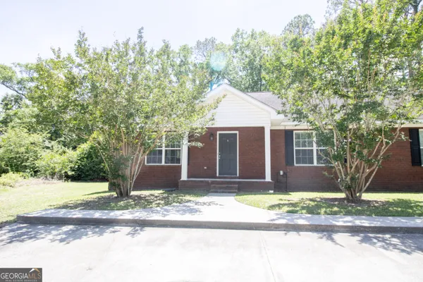 a front view of a house with a yard and tree s