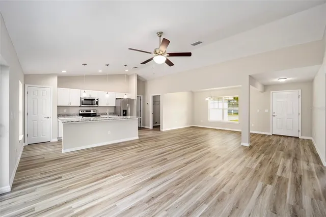 a view of kitchen with kitchen island wooden floors appliances and cabinets