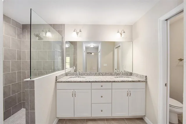 a bathroom with a granite countertop sink two mirror and a shower