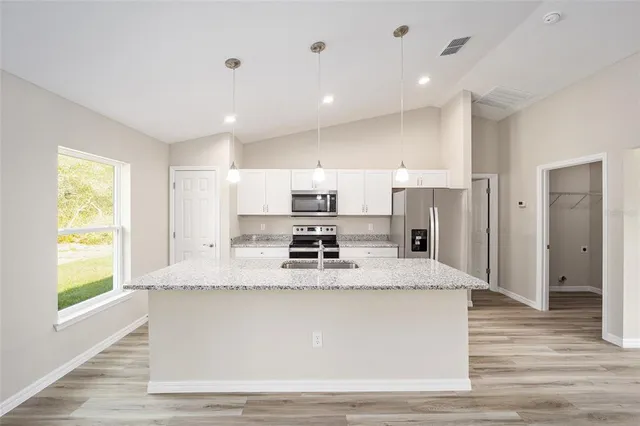 a large kitchen with stainless steel appliances kitchen island a large counter top and a refrigerator