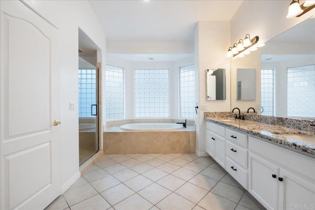 9144 Old Castle Road Valley Center, CA 92082 - Photo 20 of 48 a spacious bathroom with a granite countertop sink a mirror and a bathtub