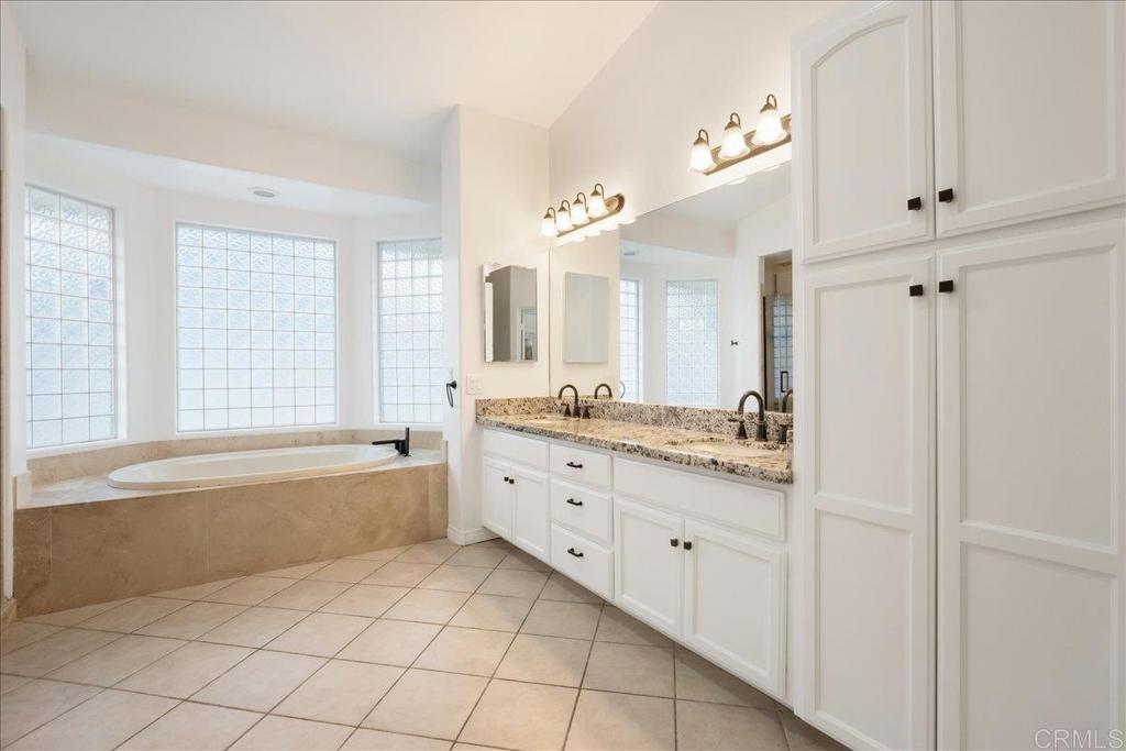 9144 Old Castle Road Valley Center, CA 92082 - Photo 21 of 48 a bathroom with a granite countertop sink a mirror a bathtub and next to a window
