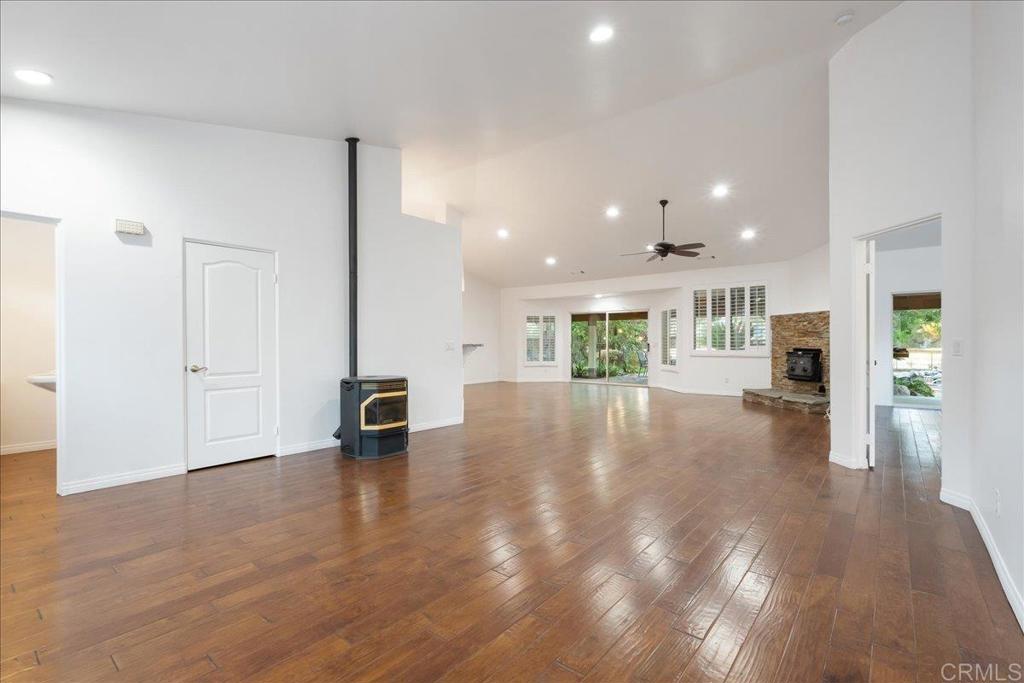 9144 Old Castle Road Valley Center, CA 92082 - Photo 10 of 48 a view of an empty room and kitchen with furniture wooden floor and windows