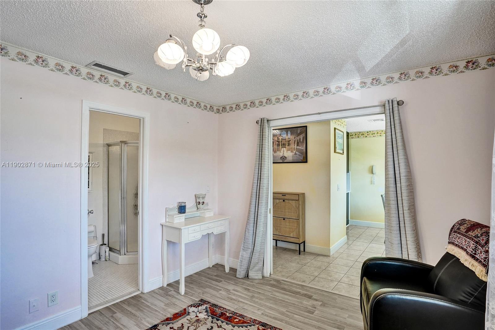 1450 Northwest 18th Avenue, Unit 203 Delray Beach, FL 33445 - Photo 21 of 30 a spacious bedroom with a bed and a chandelier