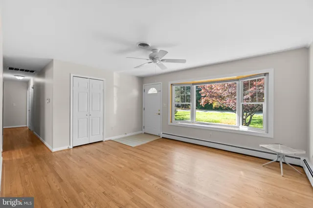 a view of an empty room with a window and wooden floor