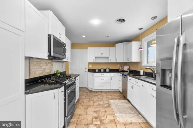 a kitchen with stainless steel appliances granite countertop a stove a sink and a refrigerator