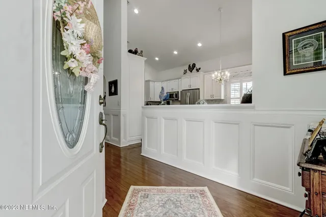 a kitchen with granite countertop a refrigerator a sink dishwasher a stove and white cabinets with wooden floor